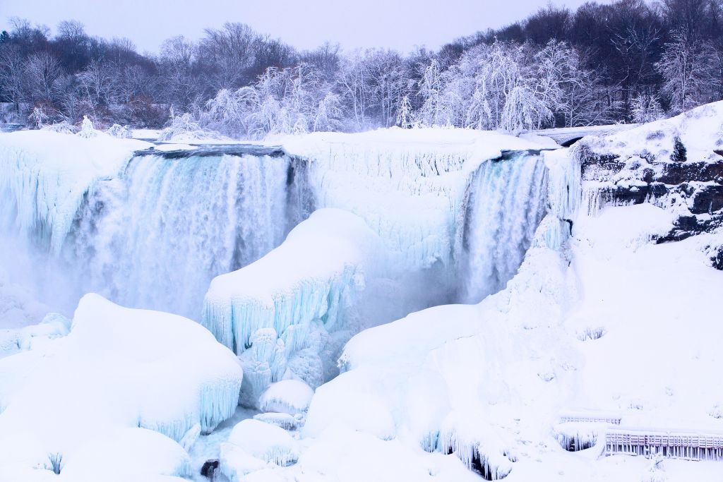 Niagara Falls completely frozen and surrounded by snow in the winter during the best time to go to Niagara Falls. 
