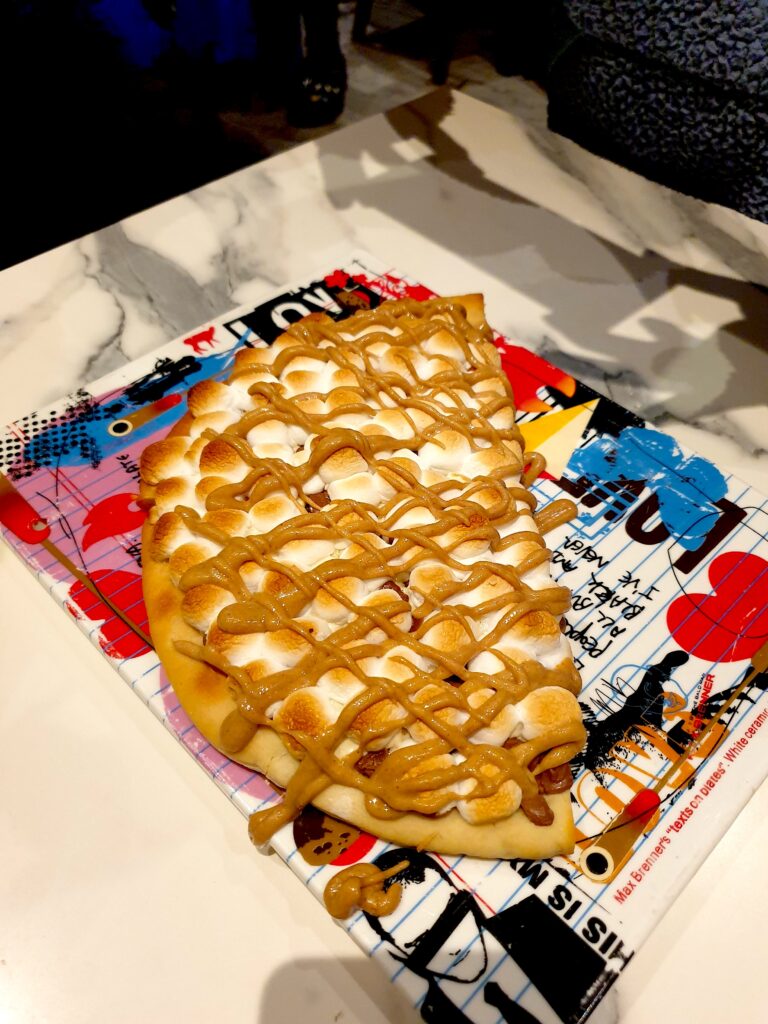 Aerial view of a dessert pizza covered in marshmallows with peanut butter sauce on top. 