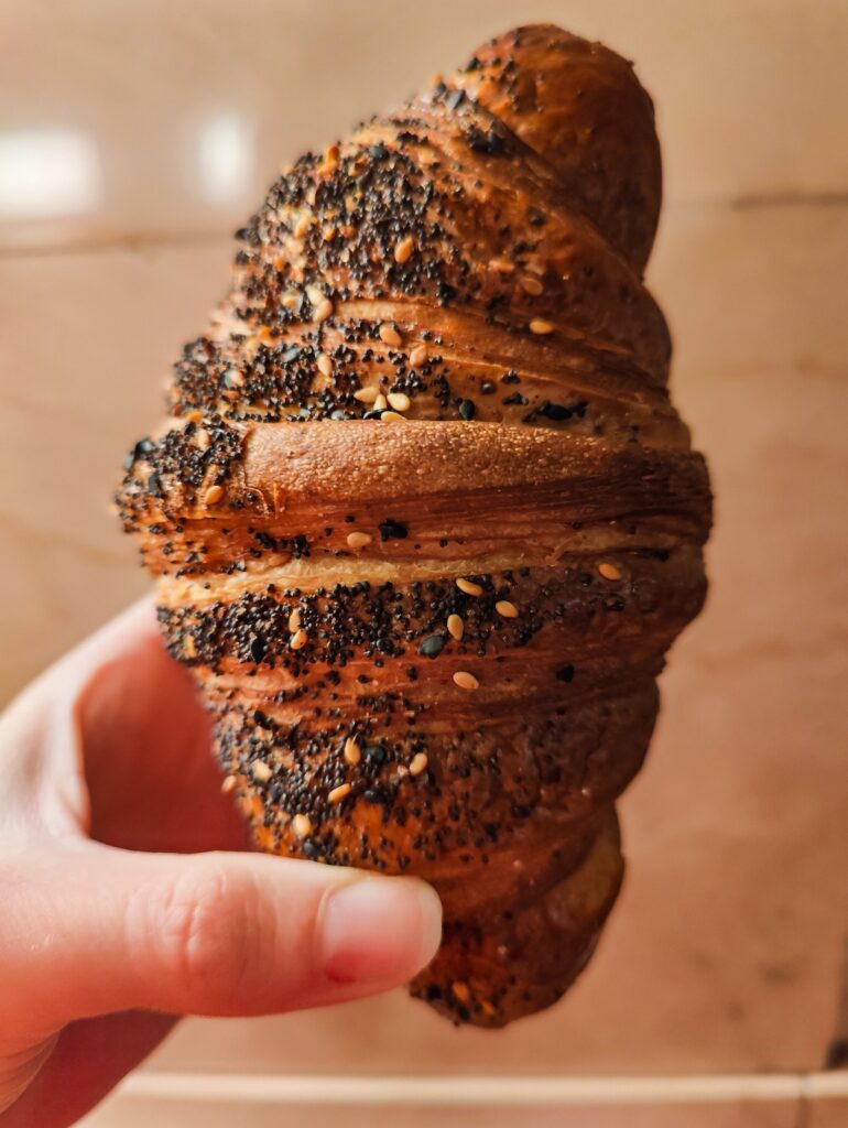 Me holding a croissant vertically from Bourke Street Bakery in Grand Central. 