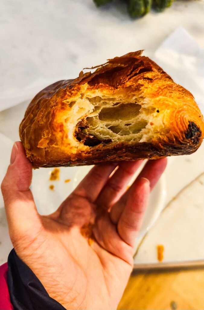 View of the inside of my espresso pain au chocolate croissant from Librae Bakery in NYC. I am holding it and you can see my purple jacket sleeve. 