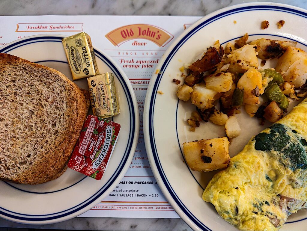 Aerial view of toast on one plate and hashbrowns/omelet from Old John's Diner. 